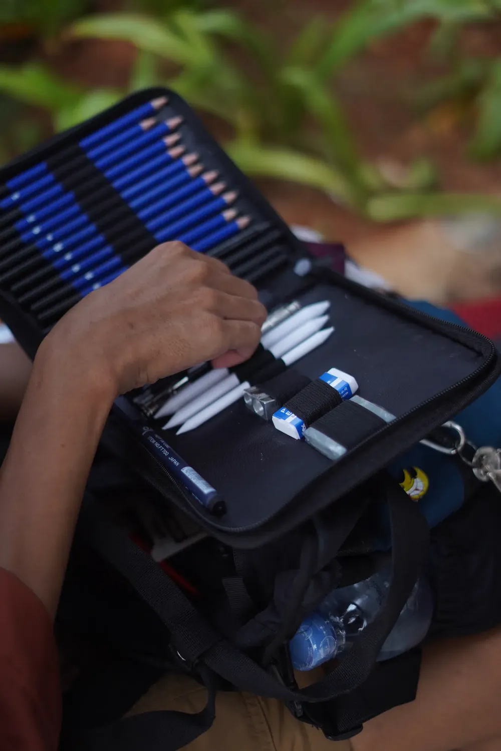 Tangan mengambil pensil dari tas alat gambar
