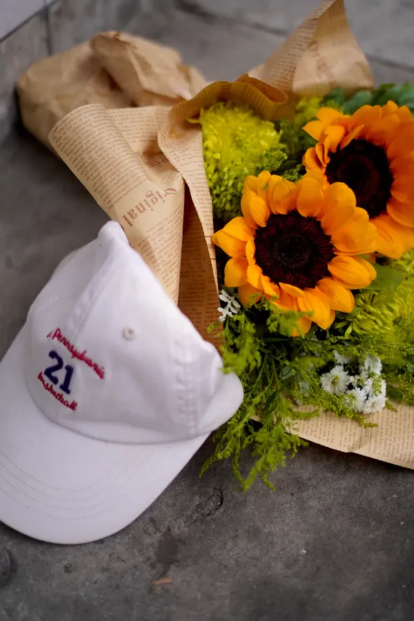 Topi putih dan buket bunga matahari di atas trotoar